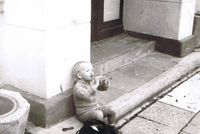 Ein Foto aus DDR-Zeiten: Simon sitzt als Kind am Straßenrand und trinkt aus irgendeiner Flasche.